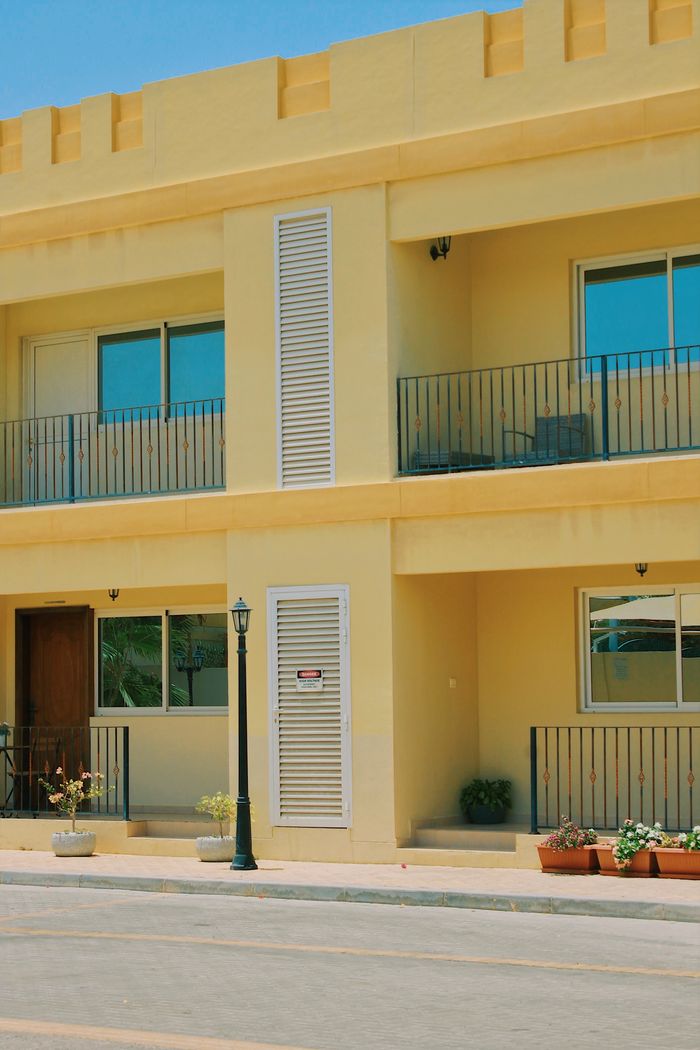Bright yellow apartment building with balconies on a sunny day.